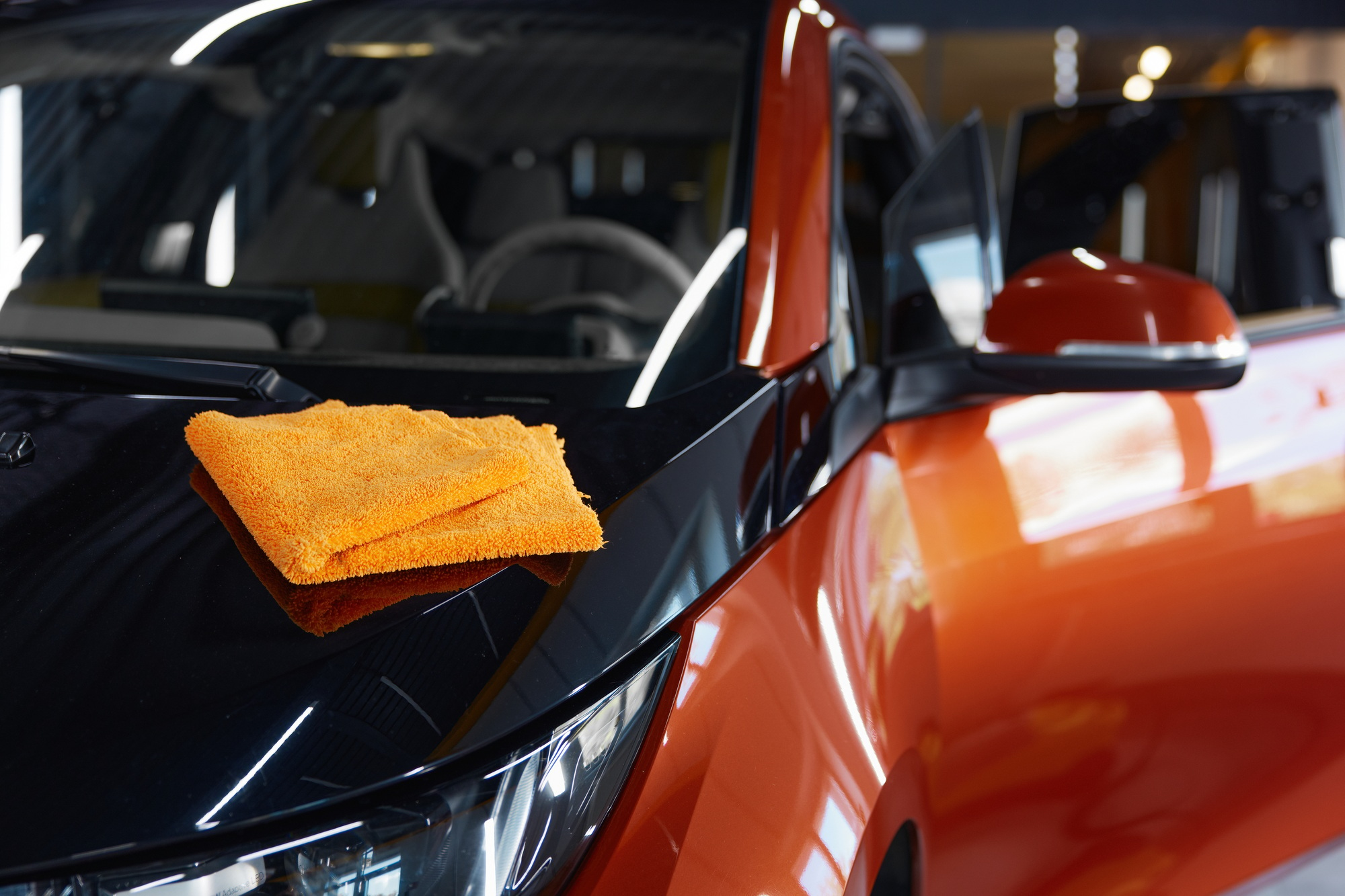 Microfiber towel cloth on shiny glossy surface of polished car