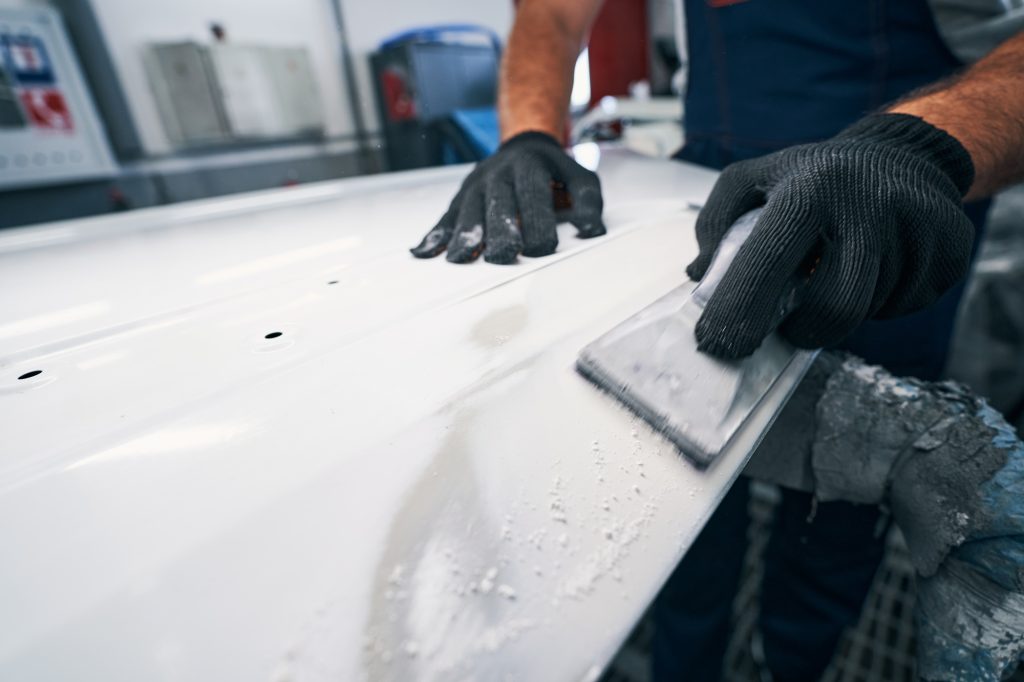 Mechanic sanding car body with hand tool